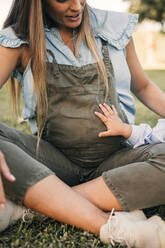 Daughter's hand touching pregnant mother abdomen at ranch - GRCF01089