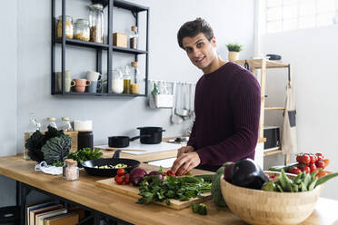 Young cutting vegetables while preparing food in kitchen - GIOF14092