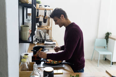 Happy man preparing food in kitchen - GIOF14095