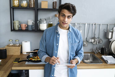 Man with digital tablet standing in kitchen at home - GIOF14097