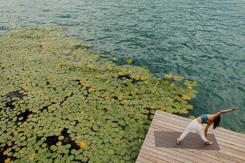 Woman doing stretching exercise on jetty - DAWF02173