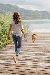 Frau und Hund beim Spaziergang auf dem Bootssteg - DAWF02179