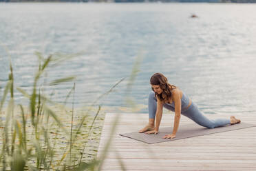Aktive Frau übt Yoga auf dem Bootssteg - DAWF02182