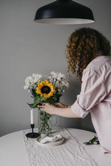 Frau arrangiert Blumen in einer Vase zu Hause - SEAF00021