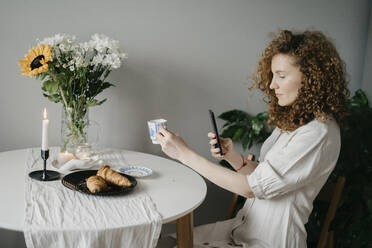 Frau fotografiert Tasse auf einem Stuhl zu Hause - SEAF00031