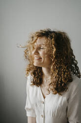 Curly haired woman with eyes closed smiling at home - SEAF00033