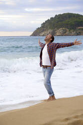 Man with arms outstretched screaming at beach - VEGF05177