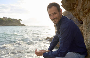 Smiling man enjoying by sea at sunset - VEGF05190