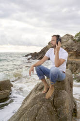Mann hört Musik über Kopfhörer am Strand - VEGF05203