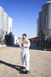 Worker in protective suit at factory on sunny day - VEGF05227