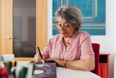 Senior woman painting on canvas at home - GPF00141
