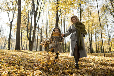 Verspieltes Mädchen und Mutter haben Spaß im Herbst Park - LLUF00333