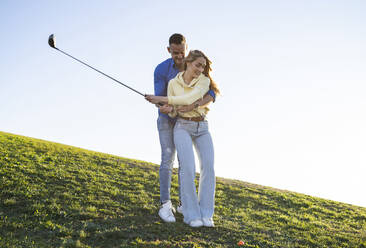 Paar mit Golfspiel auf Gras bei Sonnenuntergang - JCCMF04505