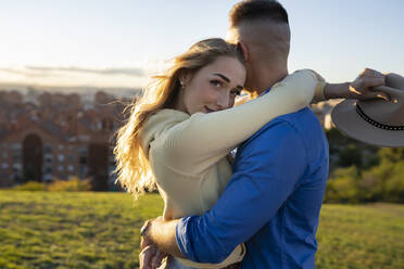 Young girlfriend hugging boyfriend at sunset - JCCMF04512