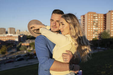 Blond woman embracing man in city - JCCMF04513