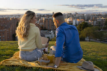 Couple enjoying picnic on hill at sunset - JCCMF04520