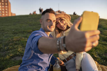 Lächelndes Paar nimmt Selfie durch Smartphone bei Sonnenuntergang - JCCMF04524