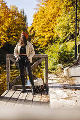 Woman with hands in pockets standing at jetty - DAWF02212