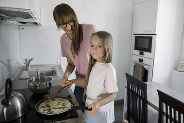 Mädchen bereitet Pfannkuchen mit Frau zu Hause vor - LLUF00339