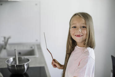 Lächelndes Mädchen hält Spachtel in der Küche - LLUF00341