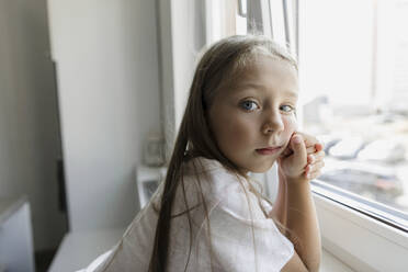 Girl leaning on window sill at home - LLUF00345