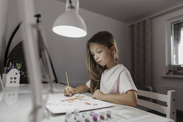 Girl painting on paper at desk - LLUF00353