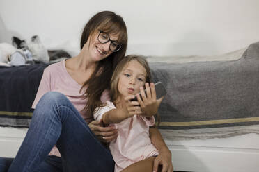 Mädchen nimmt Selfie mit Frau durch Handy zu Hause - LLUF00359