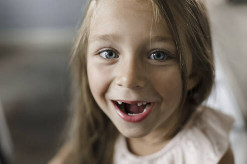 Mädchen lächelt mit Zahnlücke zu Hause - LLUF00365