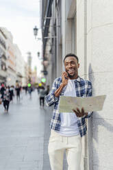 Man with map talking on smart phone at city street - PGF00911