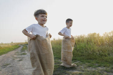 Siblings enjoying sack race at meadow - TYF00033