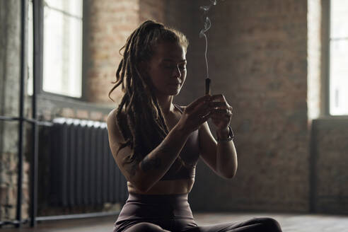 Sportler mit Rauch aus Sandelholz beim Meditieren im Yogastudio - DSHF00046