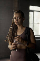 Young sportswoman with locs hairstyle holding water bottle - DSHF00062