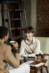 Happy teenage girl talking with boyfriend having tea in cafe - DSHF00079