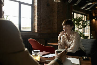 Smiling teenage girl looking at boyfriend in cafe - DSHF00081