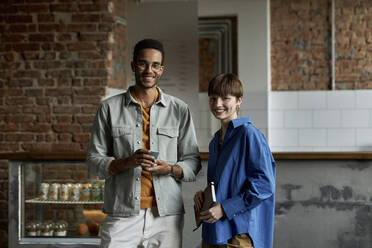 Smiling couple standing in modern cafe - DSHF00088