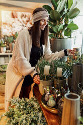 Smiling woman choosing plants at flower shop - DAWF02231