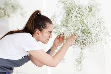 Woman florist decorator decorates wedding interior with flowers - CAVF95134