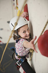 Mädchen klettert an einer Indoor-Kletterwand in London - CAVF95203