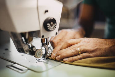 Modedesigner näht Kleidung an einer Maschine in einer Werkstatt - DAWF02268