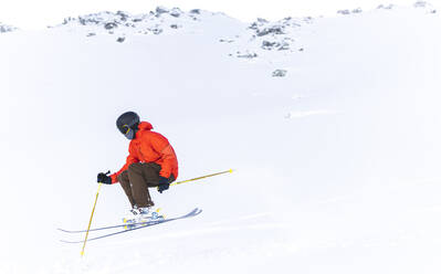 Mann in roter Jacke beim Skifahren auf einem schneebedeckten Berg - JAQF00903