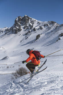 Tourist mit Rucksack beim Skifahren auf einem schneebedeckten Berg - JAQF00911