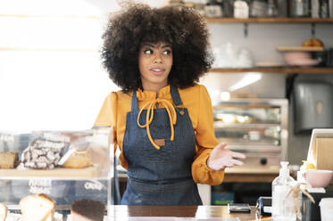 Kellnerin mit Afrofrisur an der Kaffeetheke stehend - JCCMF04534