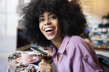 Smiling woman with pastry and coffee cup at cafe table - JCCMF04554