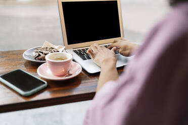 Frau benutzt Laptop auf Tisch in Café - JCCMF04556