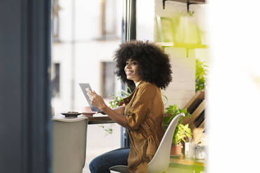 Smiling woman using mobile phone in coffee shop - JCCMF04562