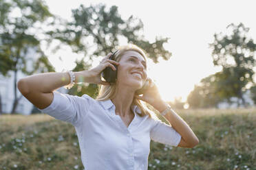 Smiling beautiful woman listening music on wireless headphones - TYF00037