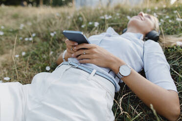Frau entspannt im Gras mit Smartphone - TYF00042