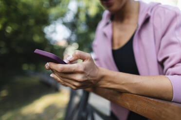 Woman leaning on railing using smart phone - TYF00052