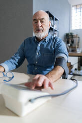 Älterer Mann mit Blutdruckmessgerät zu Hause - GIOF14117