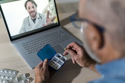 Mann hält Pillenschachtel bei Videogespräch mit Arzt zu Hause - GIOF14135